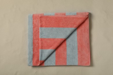 Striped beach towel on sand, top view