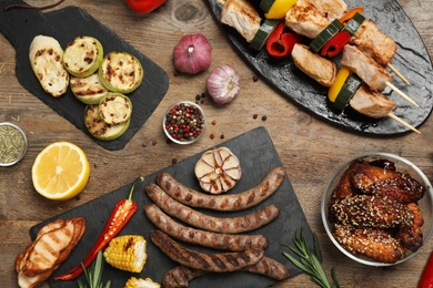 Photo of Flat lay composition with barbecued meat and vegetables on wooden table