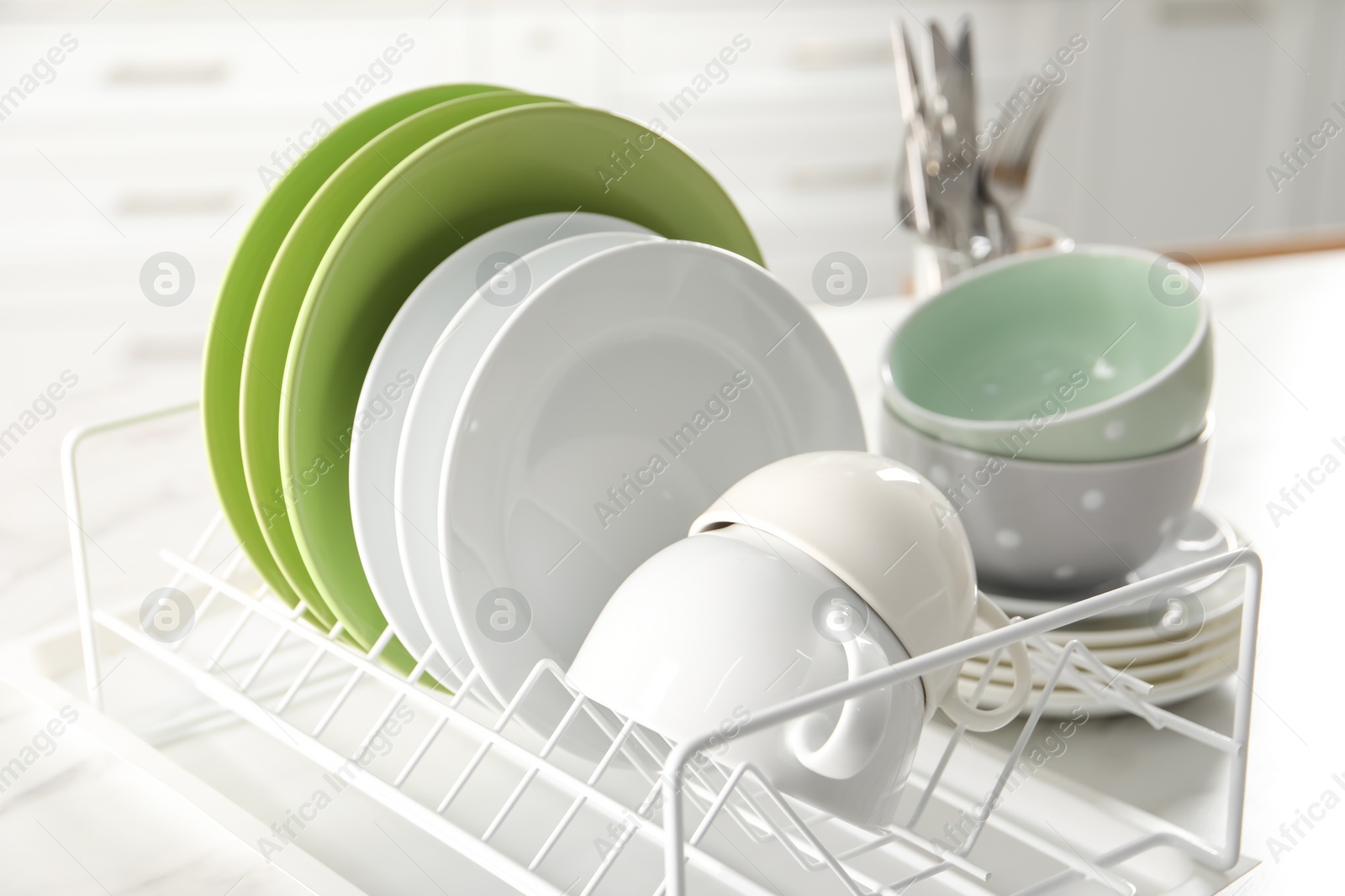 Photo of Drainer with cups and plates on white table, closeup