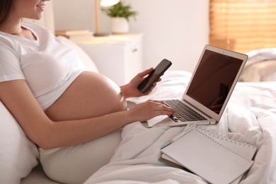 Photo of Pregnant woman working on bed at home, closeup. Maternity leave