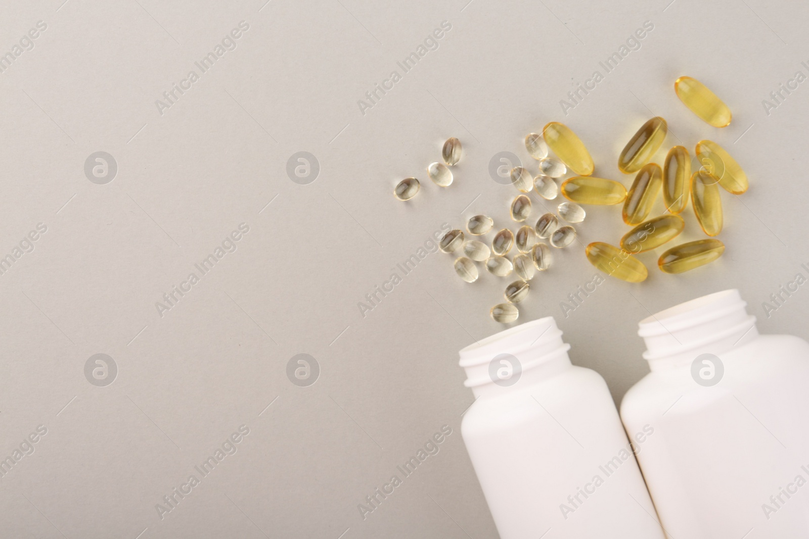 Photo of Bottles and different vitamin capsules on light grey background, flat lay. space for text