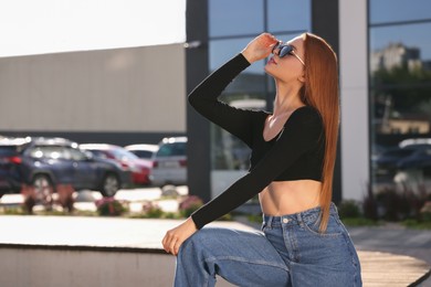 Photo of Beautiful woman in sunglasses on city street, space for text