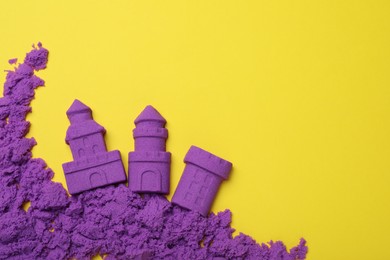 Castles made of kinetic sand on yellow background, flat lay. Space for text