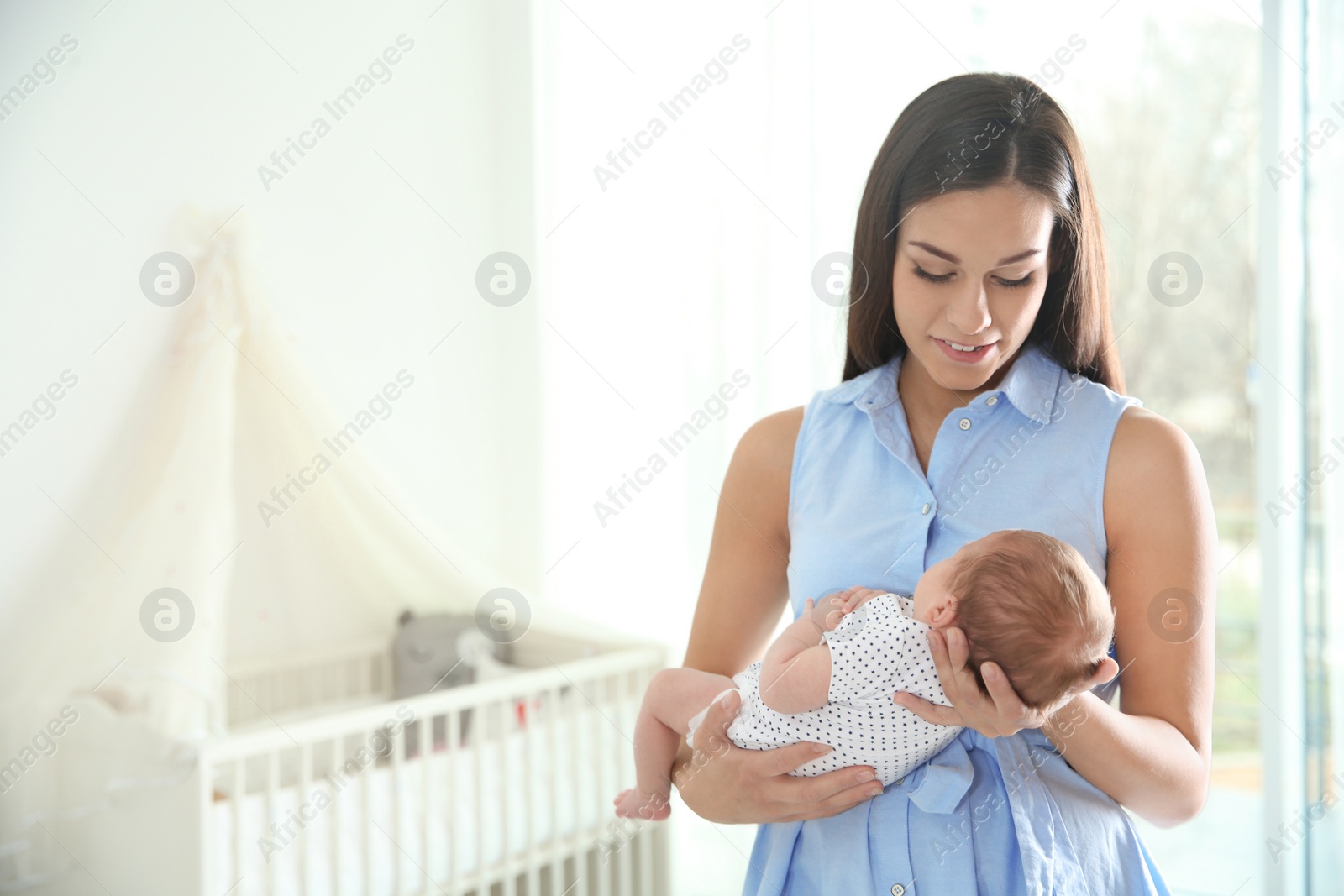 Photo of Young woman with her newborn baby at home. Space for text