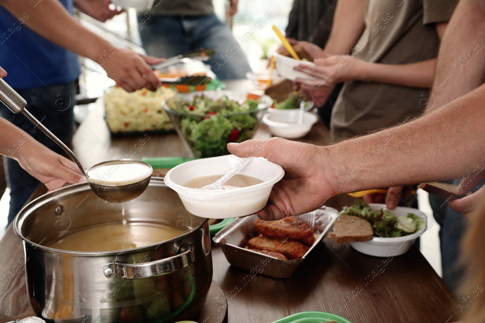 Photo of Volunteers serving food to poor people in charity centre