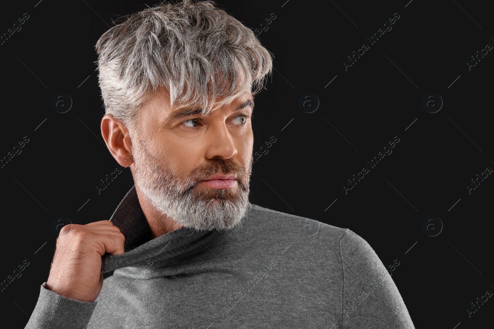 Photo of Portrait of confident man with beautiful hairstyle on black background