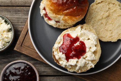 Photo of Freshly baked soda water scones with cranberry jam and butter on wooden table, flat lay