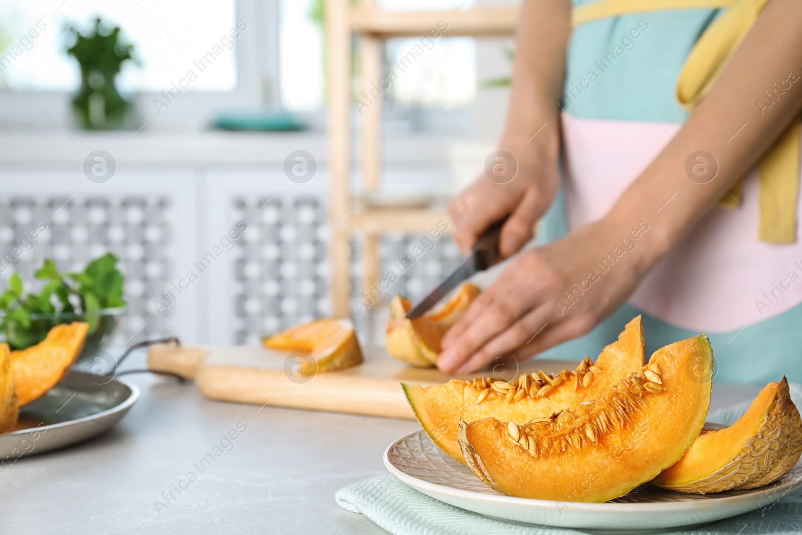 Photo of Woman slicing fresh ripe melon on light table