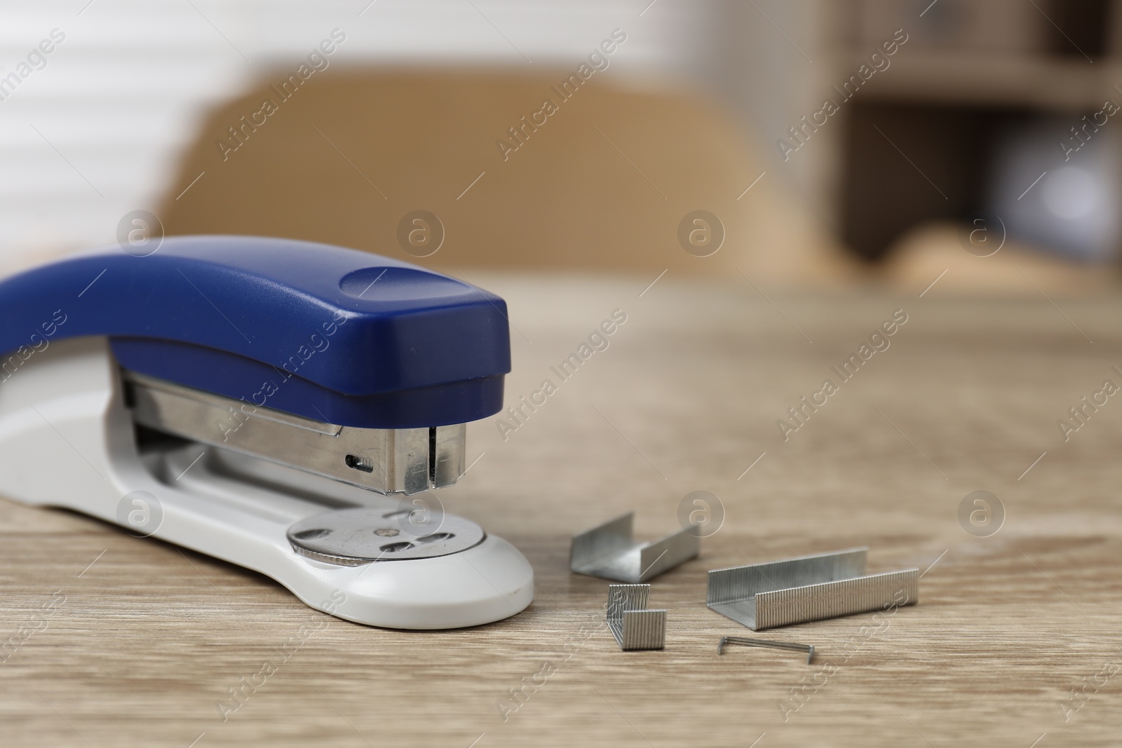 Photo of Bright stapler and metal staples on wooden table indoors, closeup