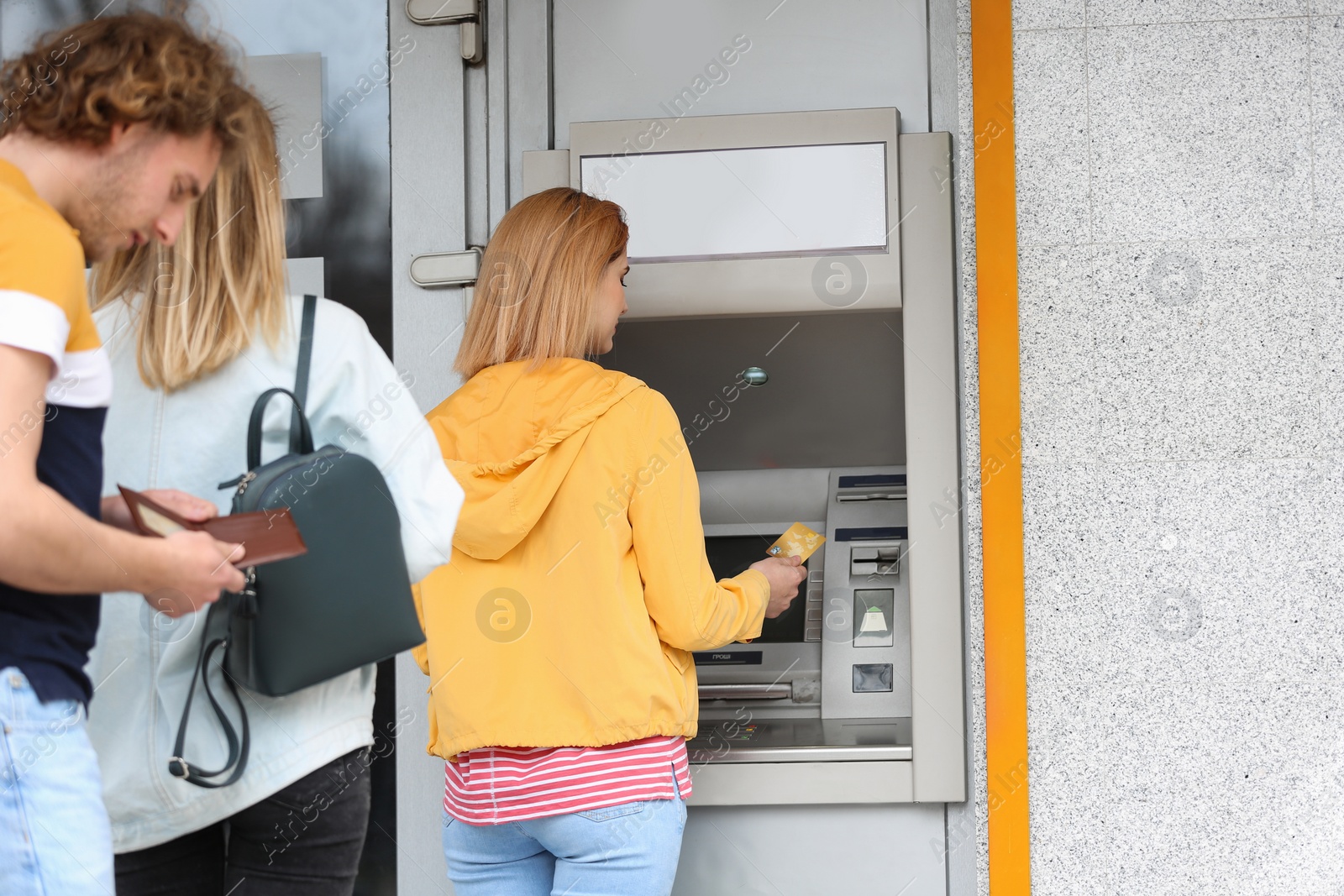 Photo of People standing in queue to cash machine outdoors