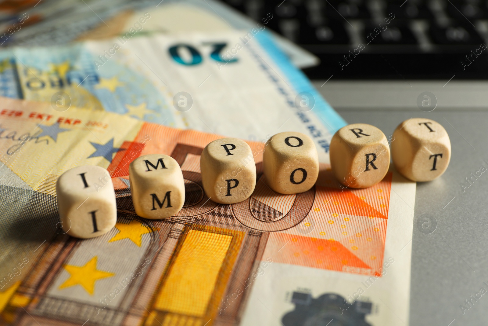 Photo of Word Import made of wooden cubes and banknotes on table, closeup