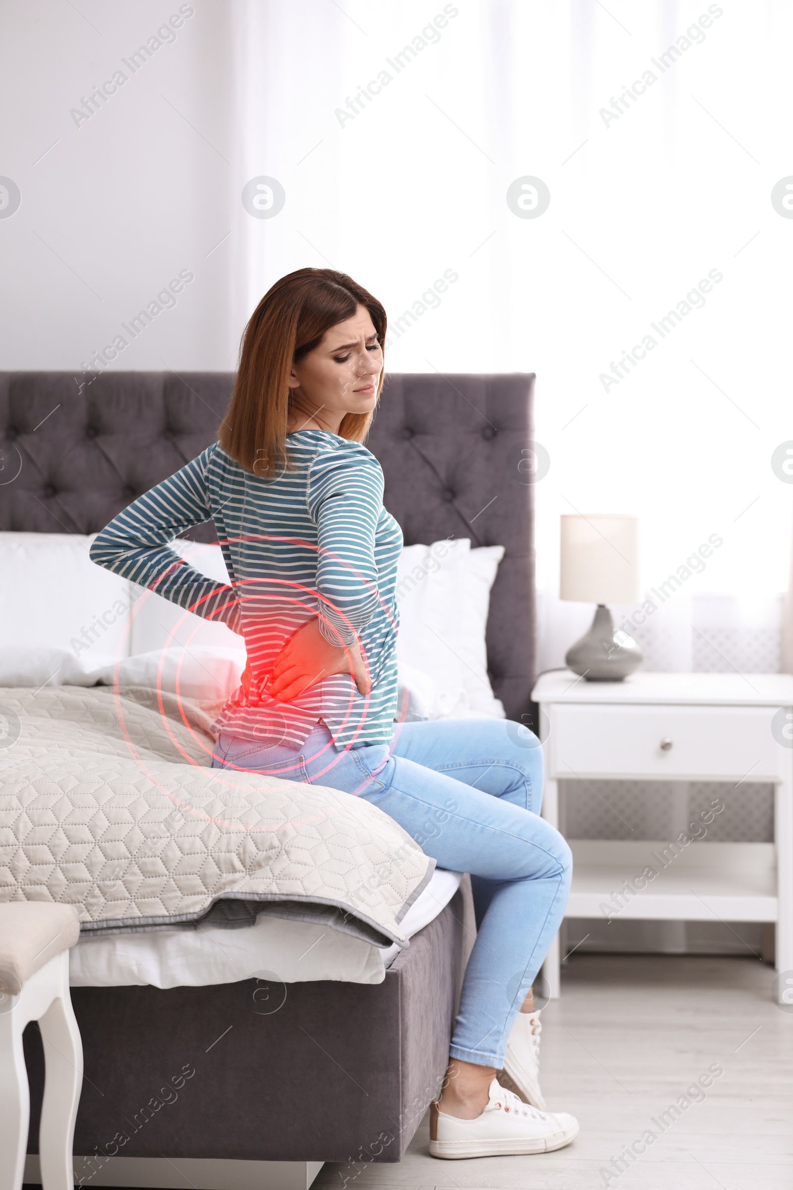 Image of Woman suffering from back pain after sleeping on uncomfortable mattress at home