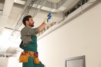 Photo of Electrician with insulting tape repairing ceiling lamp