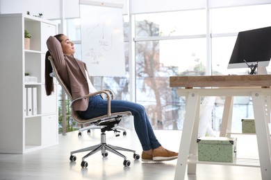 Photo of Young woman relaxing in office chair at workplace
