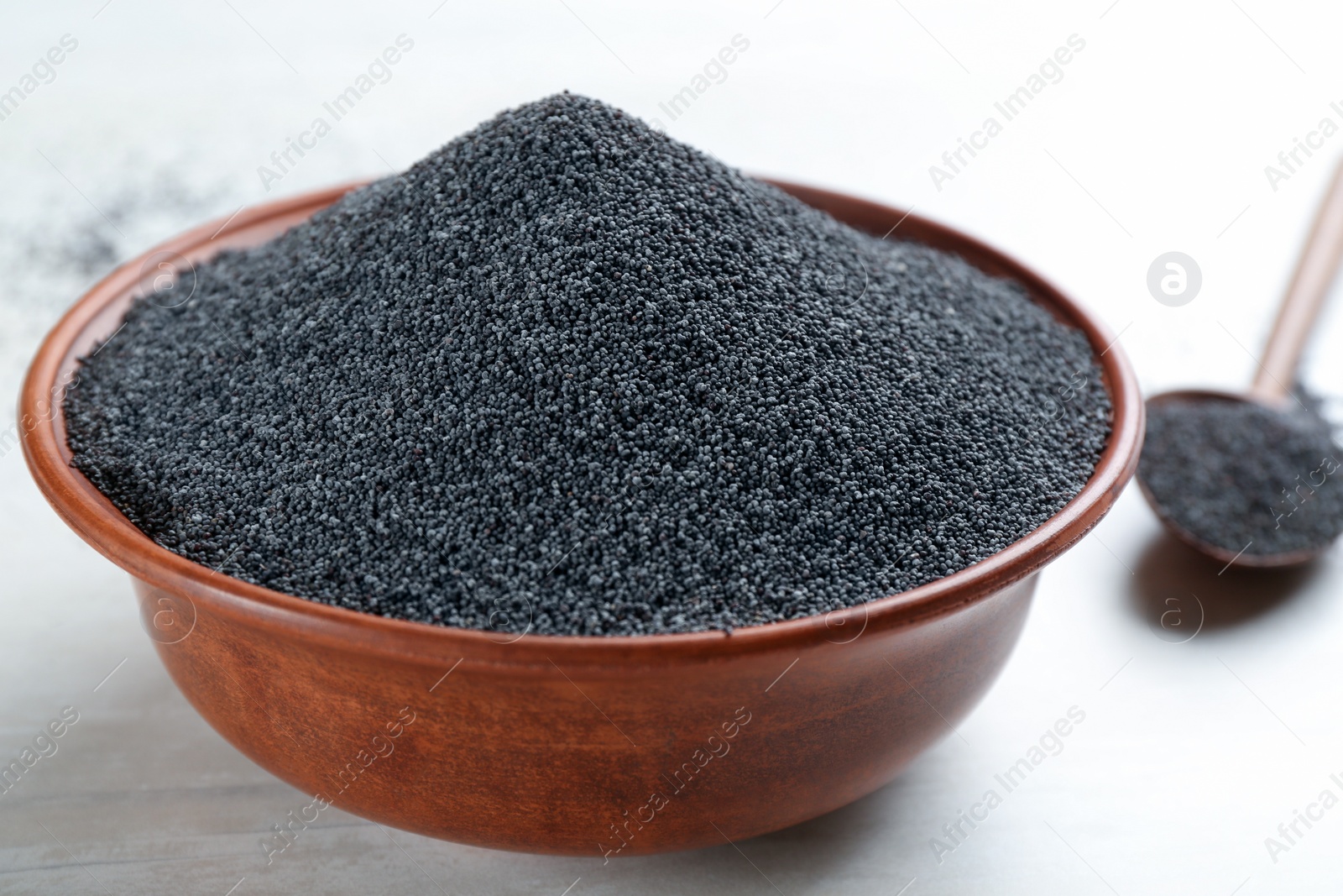 Photo of Bowl with poppy seeds on white wooden table