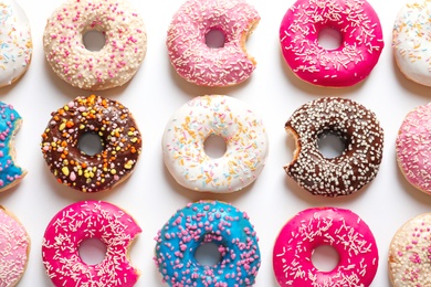 Photo of Delicious doughnuts with sprinkles on light background, top view