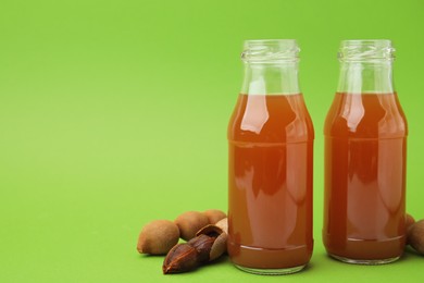 Photo of Tamarind juice and fresh fruits on green background, space for text