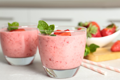 Photo of Tasty strawberry smoothie with mint in glass on light grey table