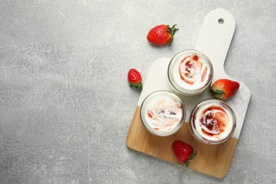 Photo of Tasty yoghurt with jam and strawberries on grey table, top view. Space for text
