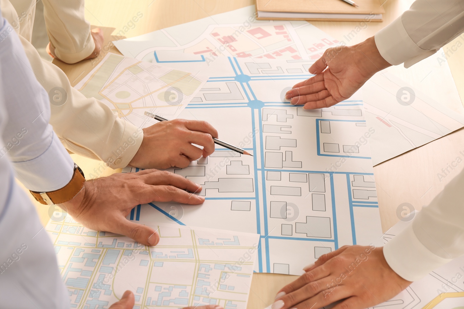 Photo of Professional cartographers working with cadastral map at table, closeup