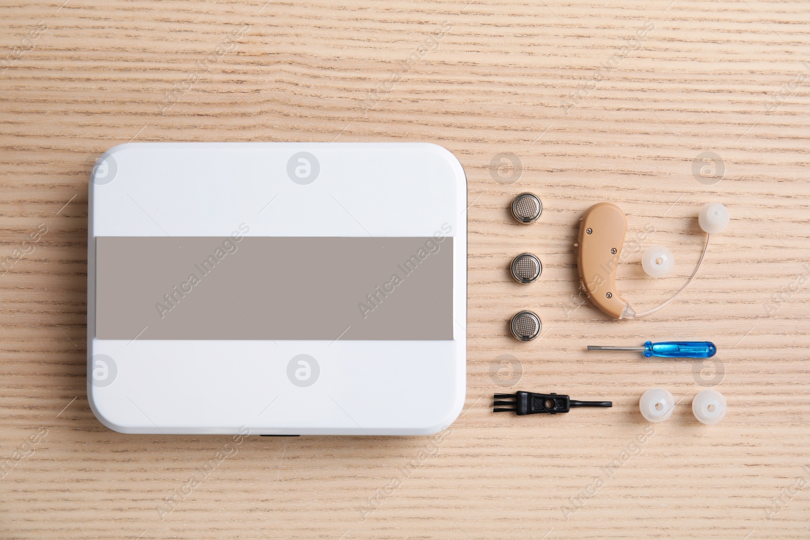 Photo of Flat lay composition with hearing aid and accessories on wooden background