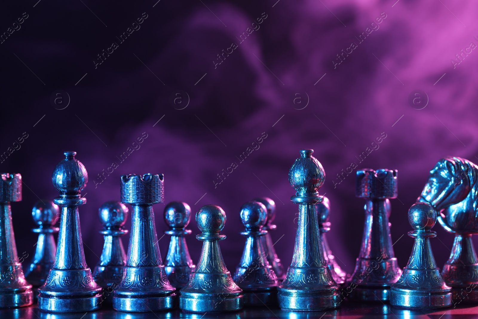 Photo of Chess pieces on checkerboard in color light. Space for text