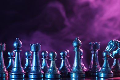 Photo of Chess pieces on checkerboard in color light. Space for text