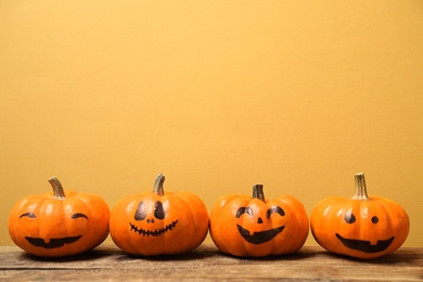 Photo of Pumpkins with scary faces on yellow background, space for text. Halloween decor