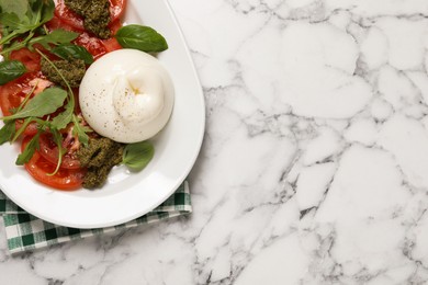 Photo of Delicious burrata salad with tomatoes, arugula and pesto sauce on white marble table, top view. Space for text