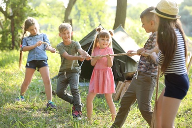 Photo of Little children pulling rope outdoors. Summer camp