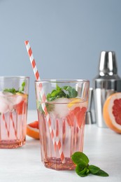 Photo of Delicious cocktail with grapefruit, mint and ice balls on white table