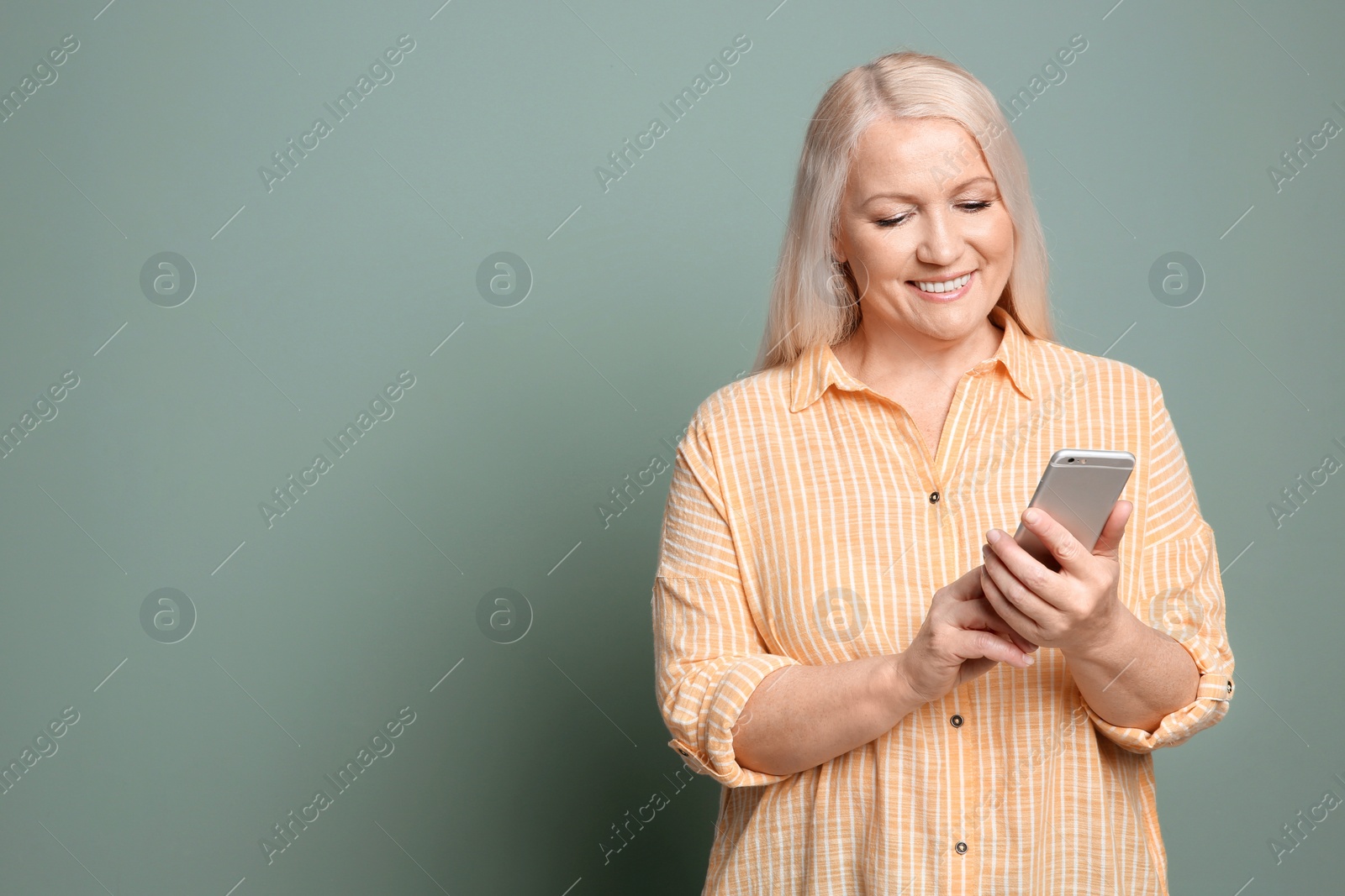 Photo of Mature woman using mobile phone on color background