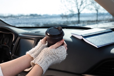 Photo of Young woman in warm gloves holding cup of coffee, closeup. Cozy atmosphere