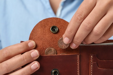 Young woman putting coin into wallet, closeup