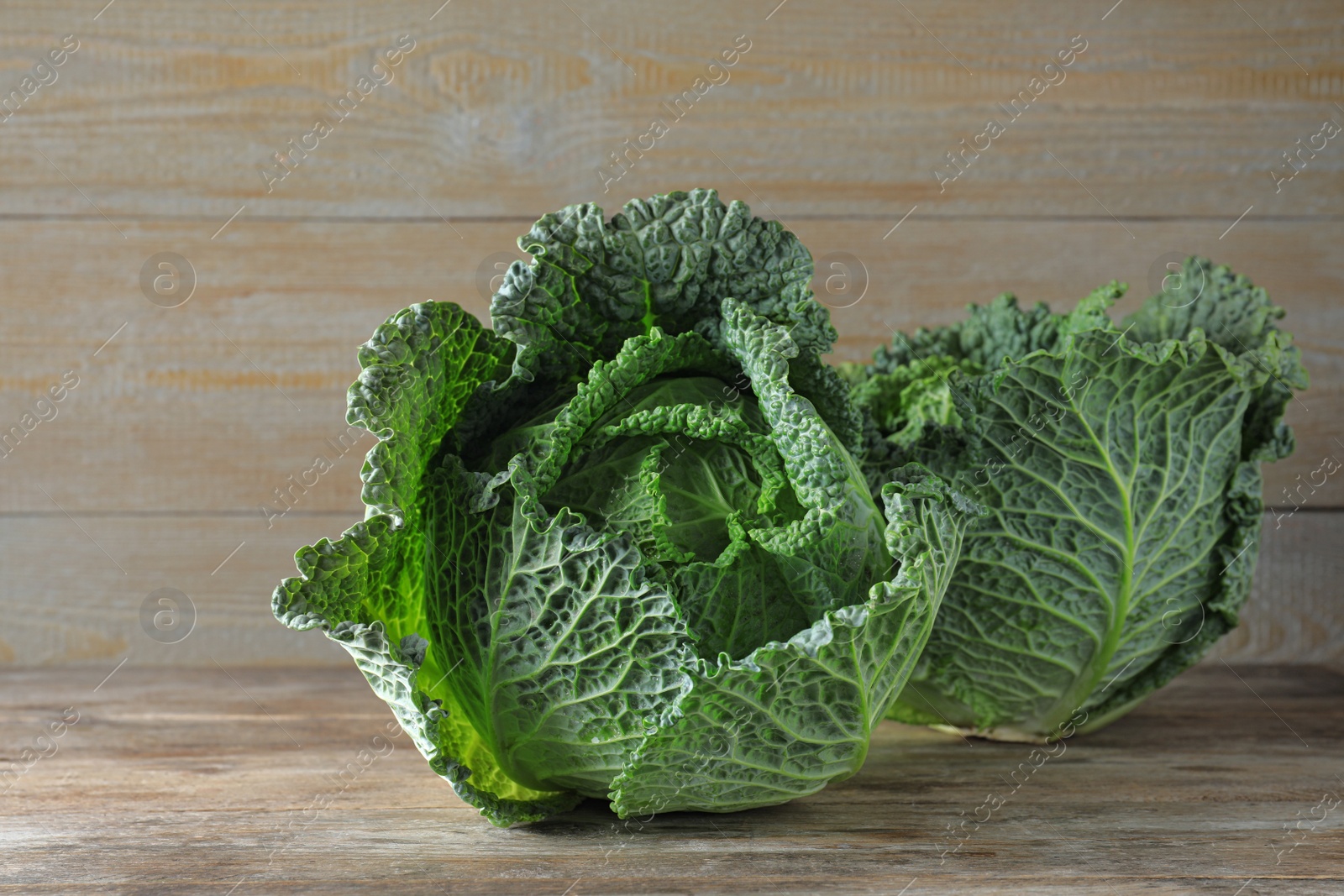 Photo of Fresh green savoy cabbages on wooden table