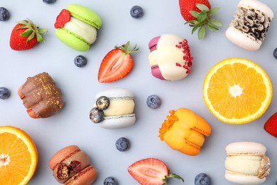 Photo of Delicious macarons, fruits and berries on light blue table, flat lay