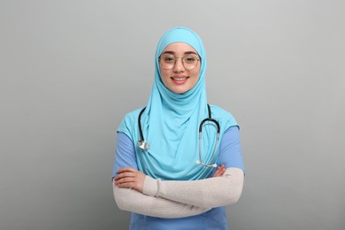 Muslim woman wearing hijab, medical uniform with stethoscope on light gray background