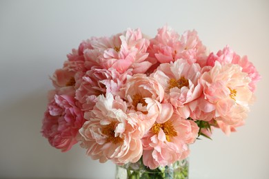Beautiful pink peonies in vase near white wall
