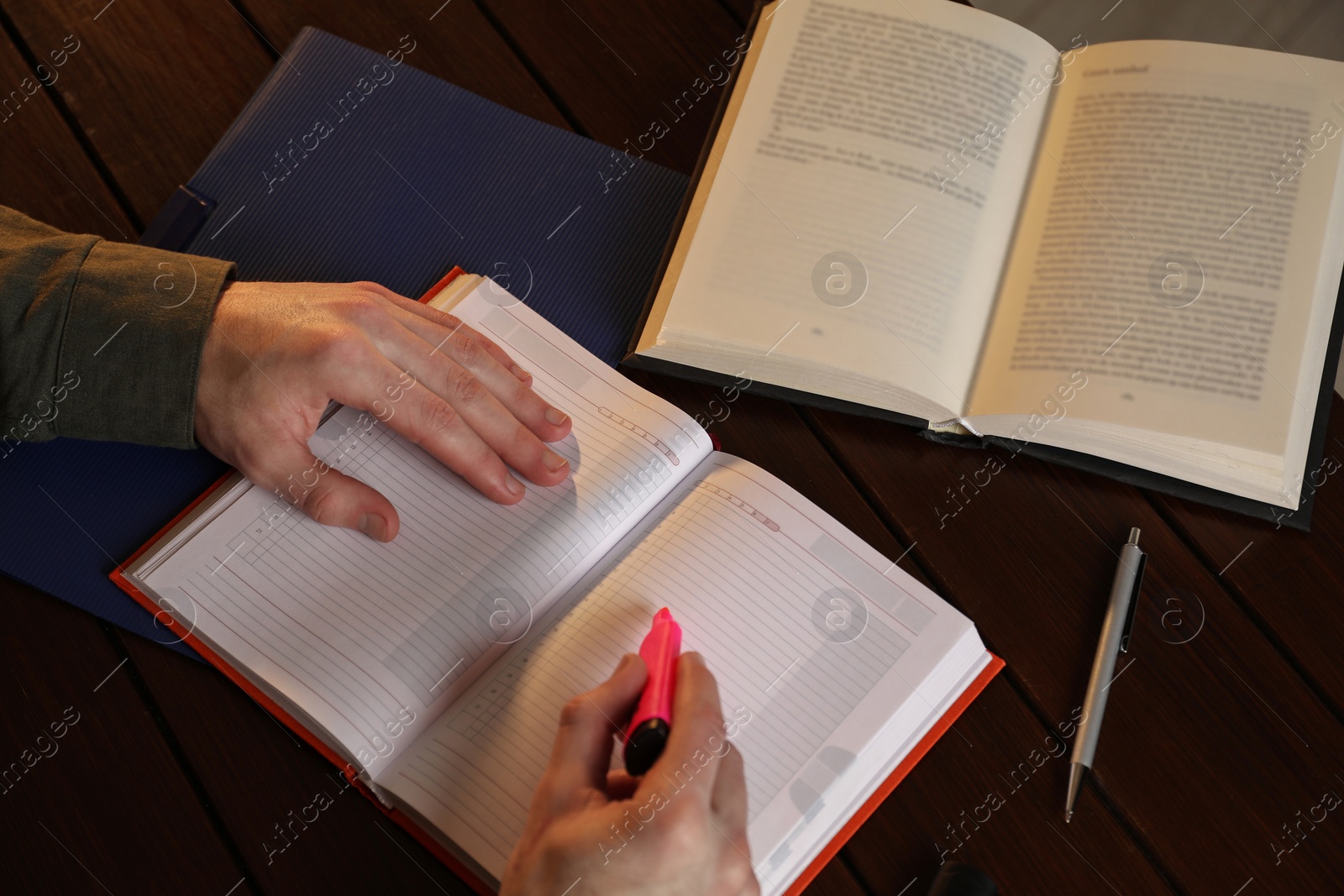 Photo of Man taking notes at wooden table in evening, above view