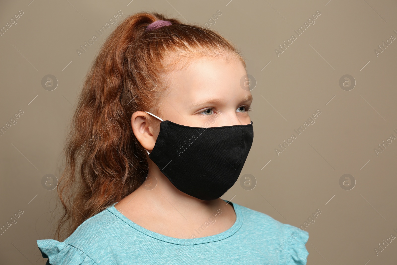 Photo of Preteen girl in protective face mask on brown background