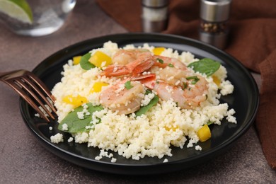 Photo of Tasty couscous with shrimps, bell pepper and basil on brown textured table, closeup