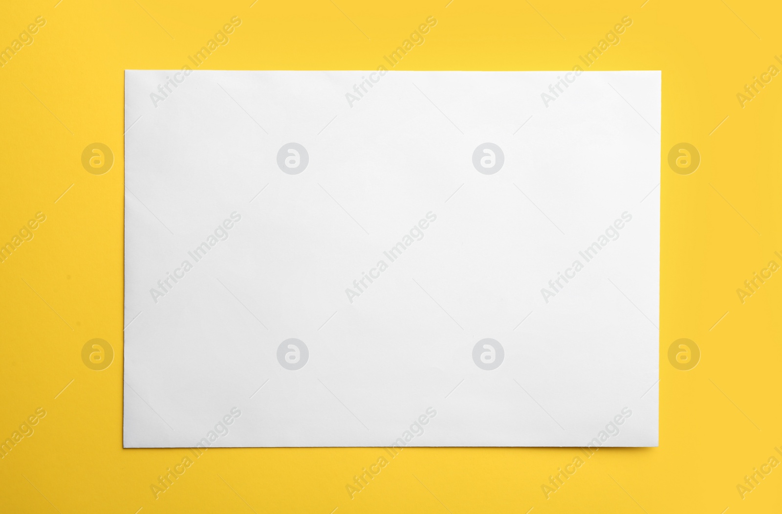 Photo of White paper envelope on yellow background, top view