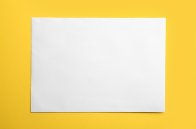 Photo of White paper envelope on yellow background, top view
