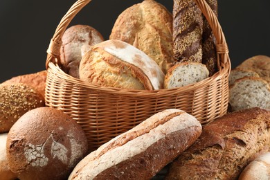 Photo of Wicker basket with different types of fresh bread against grey background