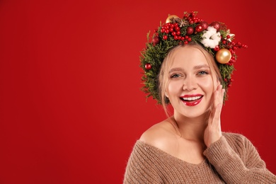 Beautiful young woman wearing Christmas wreath on red background. Space for text