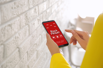 Image of Black Friday. Woman shopping online using smartphone, closeup