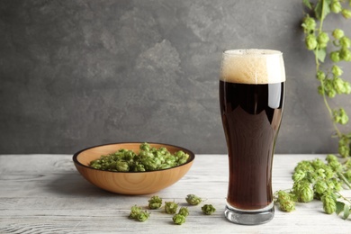 Photo of Composition with tasty beer and fresh green hops on wooden table. Space for text