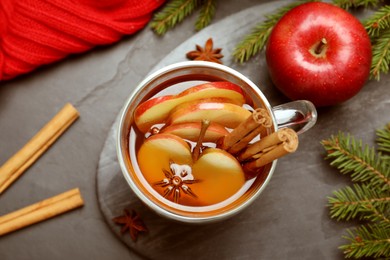 Aromatic hot mulled cider on black table, flat lay