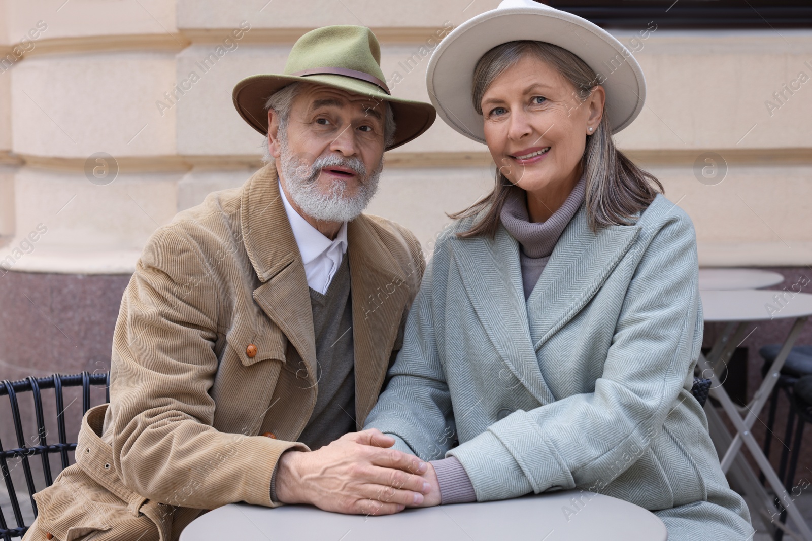 Photo of Portrait of affectionate senior couple sitting in outdoor cafe