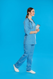 Doctor with clipboard walking on blue background